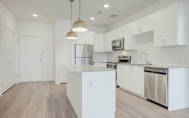 Spacious and well lit kitchen with wood flooring and stainless steel appliances
