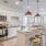 A spacious, well-lit kitchen with stainless steel appliances and granite countertops, with a living space and bedroom in the background, at The Chloe Residences in Kyle, TX.
