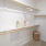 A carpeted walk-in closet with built-in shelving and overhead lighting at The Chloe apartments in Kyle, TX.
